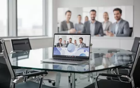 Ein moderner, heller Konferenzraum mit einem Laptop auf dem Tisch, während im Hintergrund Mitarbeiter in ein Gespräch vertieft sind. - Foto: über boerse-global.de