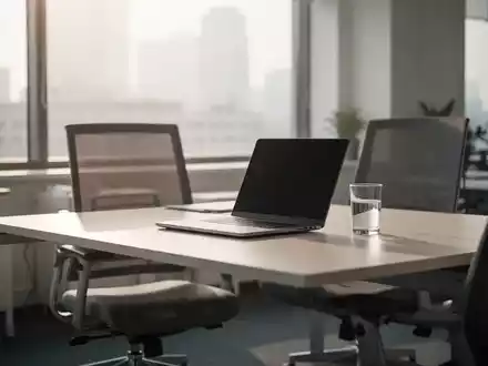 Ein leerer, aufgeräumter Büroarbeitsplatz mit einem Laptop und einem Glas Wasser vor einem hellen Fenster. - Foto: über boerse-global.de