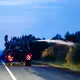 Ein landwirtschaftliches Fahrzeug wässert den Straßenrand mit Wasser aus dem Tank hinter seinem Traktor gegen die Flammen.  - Bild: Thomas Banneyer/dpa