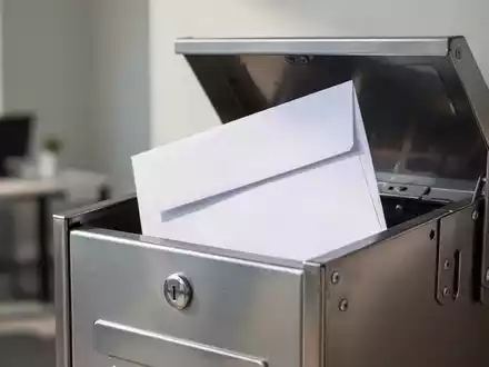 Ein weißer Geschäftsbrief liegt in einem Briefkasten, symbolisch für die rechtssichere Zustellung einer Kündigung. - Foto: über boerse-global.de