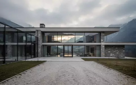 Eine moderne Luxusvilla in den Alpen bei bewölktem Himmel, umgeben von einer ruhigen Gartenanlage. - Foto: über boerse-global.de