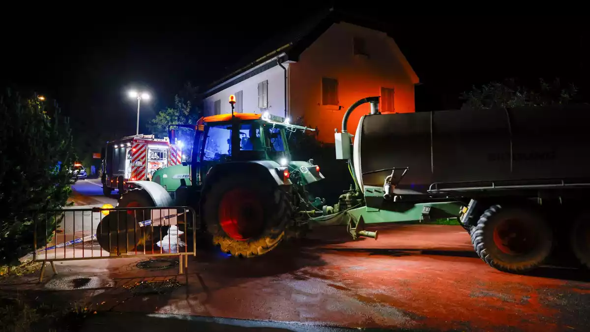 Die Feuerwehr wässert Wiesen vor Wohnbebauung. - Bild: Thomas Banneyer/dpa