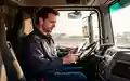 Ein LKW-Fahrer sitzt in seinem modernen Führerhaus und prüft konzentriert ein digitales Tablet. - Foto: über boerse-global.de