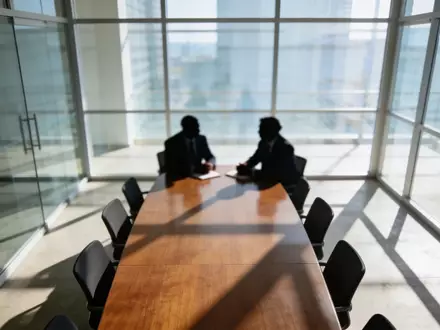 Ein moderner Konferenzraum während eines Geschäftstreffens mit unscharfen Silhouetten von Personen im Hintergrund. - Foto: über boerse-global.de