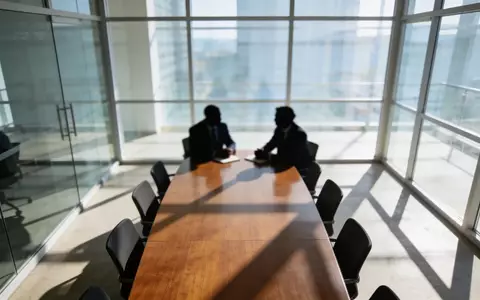 Ein moderner Konferenzraum während eines Geschäftstreffens mit unscharfen Silhouetten von Personen im Hintergrund. - Foto: über boerse-global.de