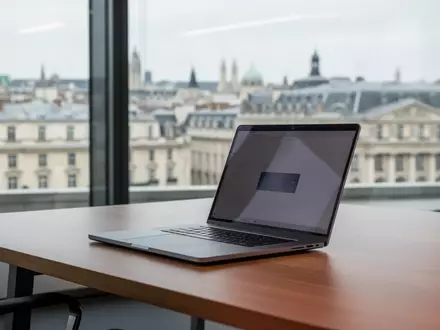Moderner Büroarbeitsplatz mit Laptop vor einem Fenster in einem europäischen Behördengebäude. - Foto: über boerse-global.de