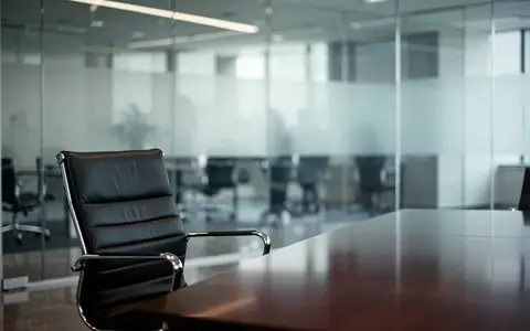 Ein minimalistisches, modernes Büro-Interieur mit einem leeren Bürostuhl und einer Glaswand, das eine Atmosphäre des organisatorischen Umbruchs vermittelt. - Foto: über boerse-global.de