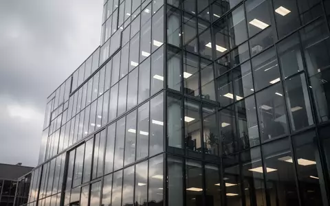 Moderne Glasfassade eines Bürogebäudes an einem bewölkten Tag. - Foto: über boerse-global.de