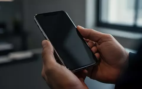 Ein Smartphone in der Hand einer Person in einem professionellen Büro, symbolisiert digitale Sicherheit und Datenschutz. - Foto: über boerse-global.de