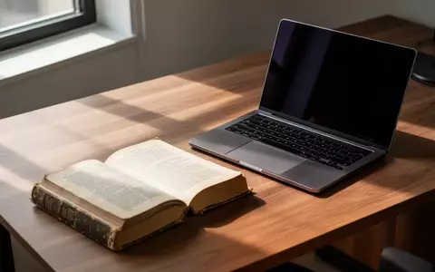 Ein offenes Buch und ein Laptop auf einem Holztisch in einem hellen, professionellen Arbeitszimmer. - Foto: über boerse-global.de