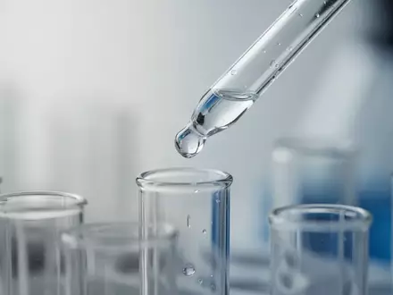 Laborumgebung mit einer Pipette, die eine klare Flüssigkeit in ein Reagenzglas abgibt, als Symbol für medizinische Forschung. - Foto: über boerse-global.de