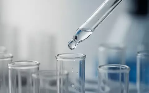 Laborumgebung mit einer Pipette, die eine klare Flüssigkeit in ein Reagenzglas abgibt, als Symbol für medizinische Forschung. - Foto: über boerse-global.de