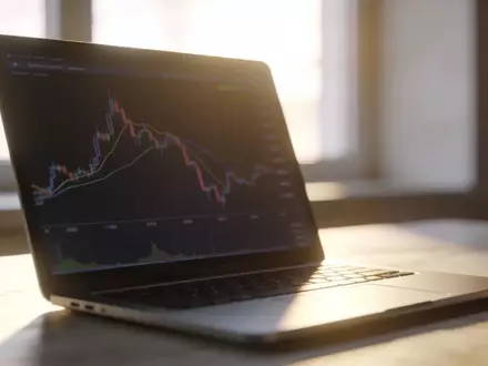 Ein moderner, aufgeräumter Arbeitsplatz mit einem Laptop, der einen neutralen Börsenchart ohne Text anzeigt. - Foto: über boerse-global.de