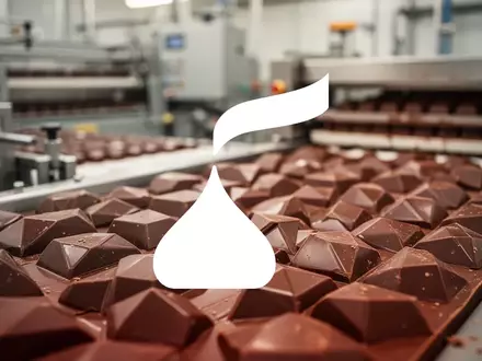 Abstrakte Darstellung einer modernen Schokoladenproduktion mit weicher Beleuchtung und industrieller Ästhetik. - Foto: über boerse-global.de