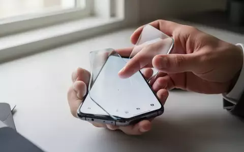 Nahaufnahme einer Hand, die ein modernes Smartphone in einer hellen, professionellen Arbeitsumgebung bedient. - Foto: über boerse-global.de