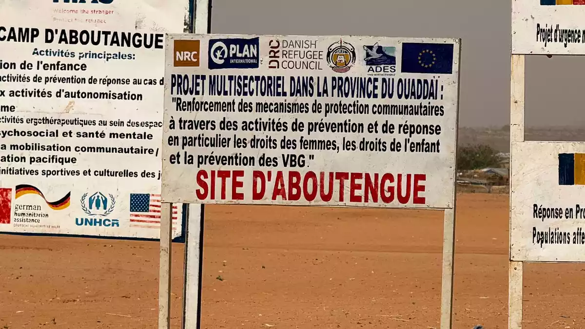 Auf dem Gelände eines Lagers für Flüchtlinge aus dem Sudan im Osten des Tschads stehen die Logos von Hilfsorganisationen, die dort im Einsatz sind. (Archivbild) - Bild: Eva Krafczyk/dpa