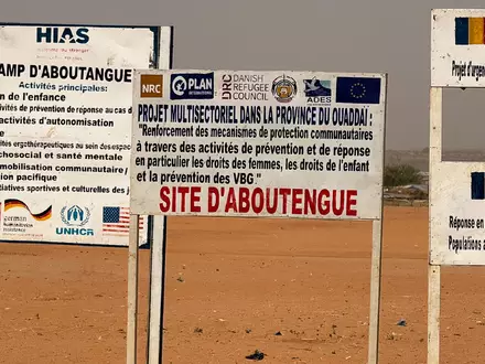 Auf dem GelĂ€nde eines Lagers fĂŒr FlĂŒchtlinge aus dem Sudan im Osten des Tschads stehen die Logos von Hilfsorganisationen, die dort im Einsatz sind. (Archivbild) - Foto: Eva Krafczyk/dpa