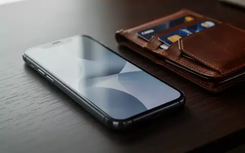 Ein Smartphone liegt neben einer Geldbörse mit Kreditkarte auf einem Schreibtisch als Symbol für digitale Sicherheitsrisiken. - Foto: über boerse-global.de