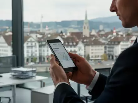 Person hält ein Smartphone in einer modernen Büroumgebung als Symbol für digitales Bezahlen in der Schweiz. - Foto: über boerse-global.de