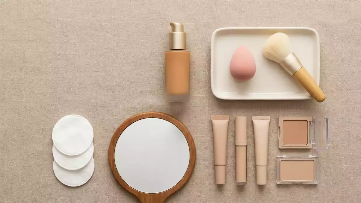 Flatlay-Arrangement rund um Fluessigfoundation mit passenden Requisiten von oben