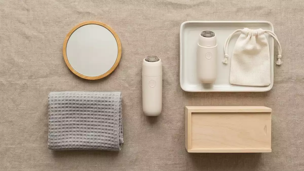 Flatlay-Arrangement rund um Gesichtshaarentferner mit passenden Requisiten von oben