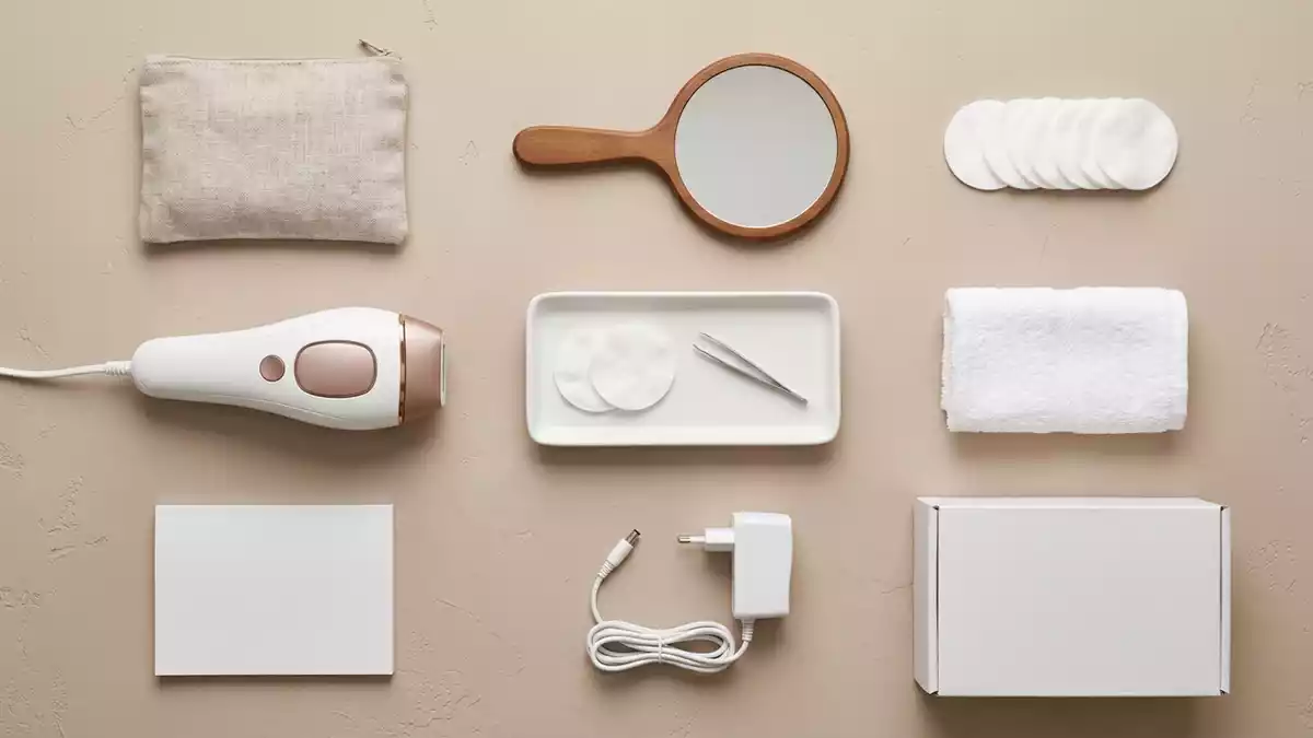 Flatlay-Arrangement rund um IPL-Haarentferner mit passenden Requisiten von oben