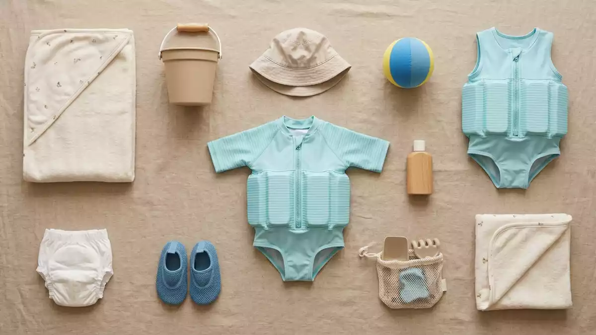 Flatlay-Arrangement rund um Baby-Schwimmanzug mit passenden Requisiten von oben