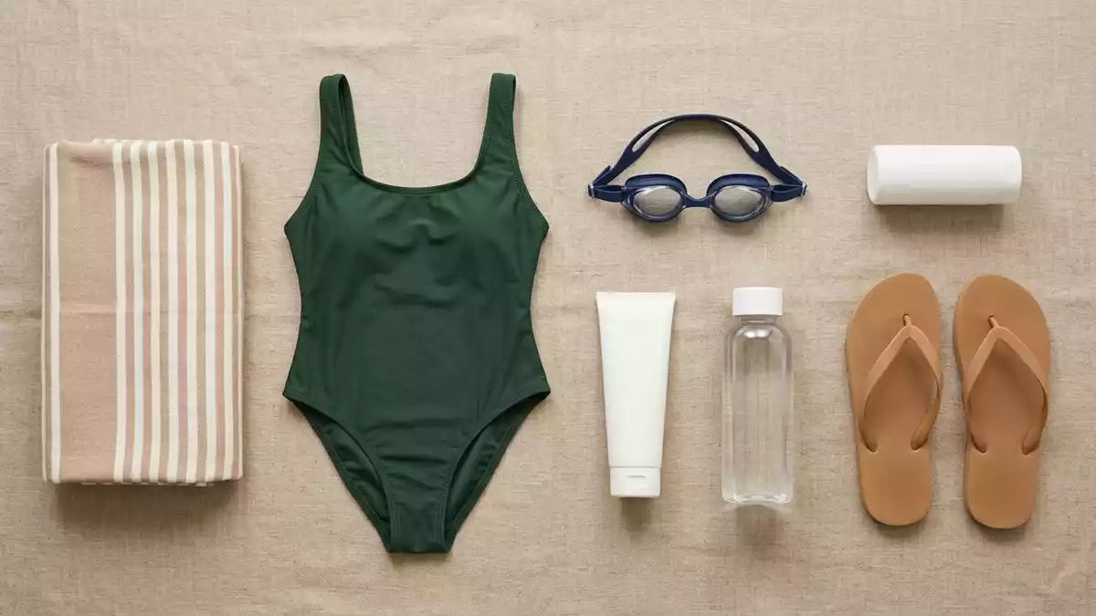 Flatlay-Arrangement rund um Badeanzug mit passenden Requisiten von oben, neutral