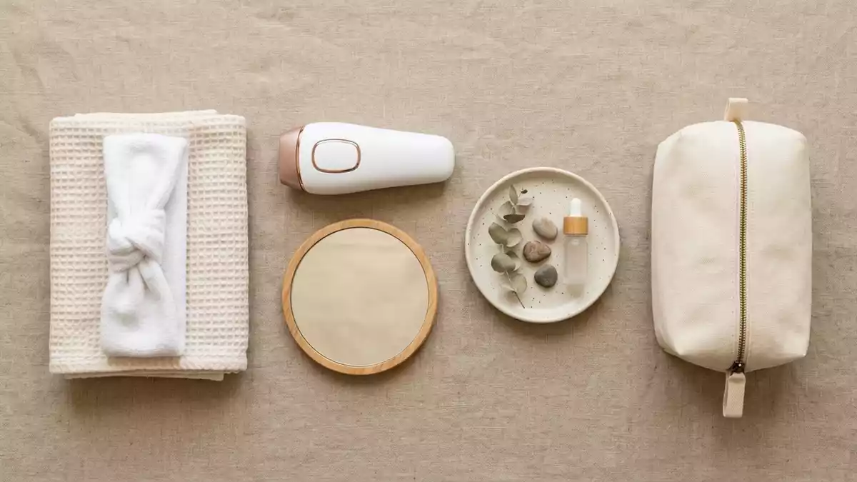 Flatlay-Arrangement rund um Haarentfernungsgeraet mit passenden Requisiten von oben