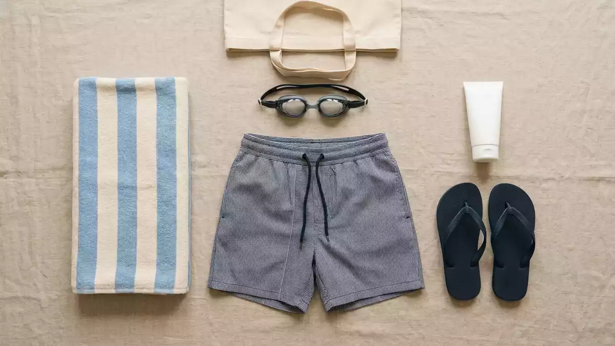 Flatlay-Arrangement rund um Badeshorts mit passenden Requisiten von oben, neutral