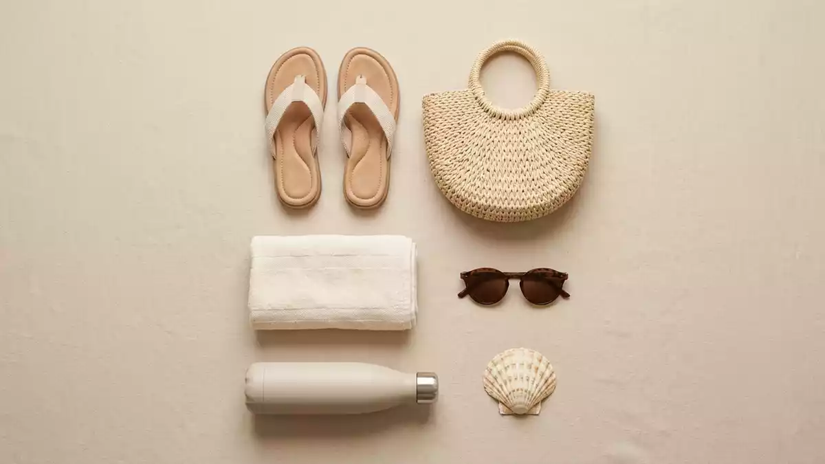 Flatlay-Arrangement rund um Damen-Sandalen mit passenden Requisiten von oben, neutral