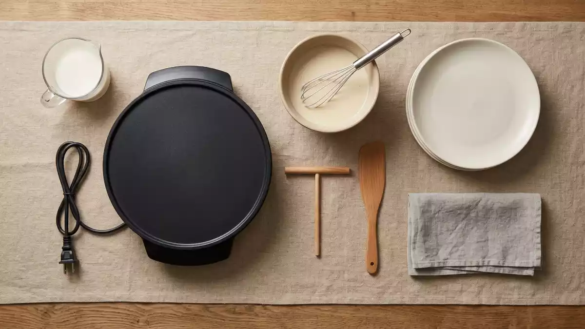 Flatlay-Arrangement rund um Crepesgeraet mit passenden Requisiten von oben, neutral