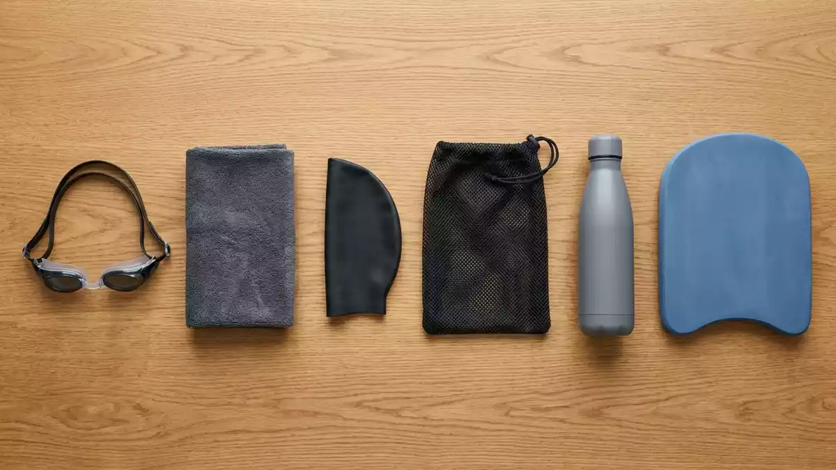 Flatlay-Arrangement rund um Schwimmbrille mit passenden Requisiten von oben, neutral