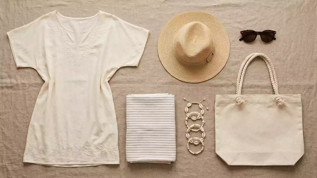 Flatlay-Arrangement rund um Strandkleid mit passenden Requisiten von oben, neutral