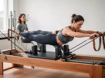 Eine Person trainiert konzentriert an einem Pilates-Reformer in einem hellen, modernen Fitnessstudio zur Stärkung der Rumpfmuskulatur. - Foto: über boerse-global.de