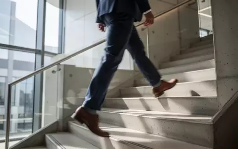 Eine Person steigt in einem hellen, modernen Treppenhaus eine Treppe hinauf, um die Herz-Kreislauf-Gesundheit zu fördern. - Foto: über boerse-global.de