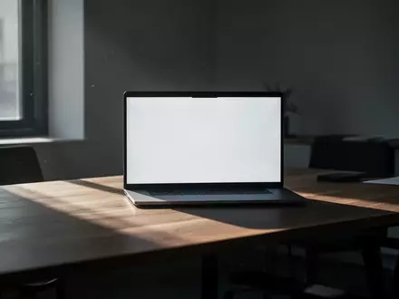 Ein minimalistischer Büroarbeitsplatz mit einem Laptop in einem dezent beleuchteten Raum. - Foto: über boerse-global.de
