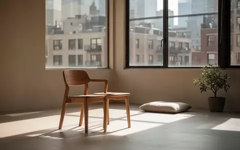 Ein minimalistischer, lichtdurchfluteter Meditationsraum mit einem Holzhocker und einem Sitzkissen in einer urbanen Umgebung. - Foto: über boerse-global.de
