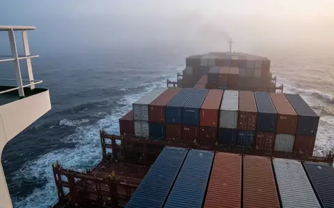 Ein großes Containerschiff auf stürmischer See bei Dämmerung, symbolisch für globale Handelsrouten und Marktunsicherheit. - Foto: über boerse-global.de