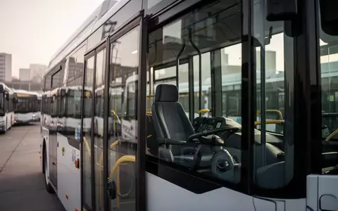 Ein moderner Stadtbus parkt in einem Depot bei Tageslicht, Fokus auf den leeren Fahrerplatz. - Foto: über boerse-global.de