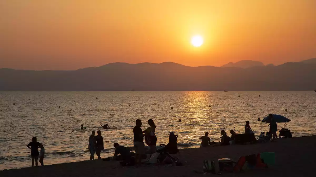 Am Strand von Playa de Palma auf Mallorca baden Menschen bei Sonnenuntergang im Meer. (Archivbild) - Bild: Clara Margais/dpa