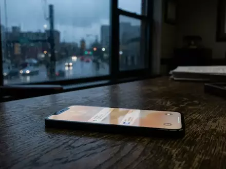 Ein Smartphone auf einem dunklen Schreibtisch in einem Regierungsbüro, das eine eingehende Benachrichtigung anzeigt. - Foto: über boerse-global.de
