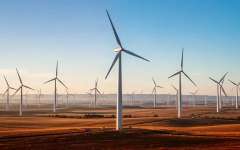 Moderne Windkraftanlagen in einer sonnendurchfluteten Landschaft bei Sonnenuntergang. - Foto: über boerse-global.de