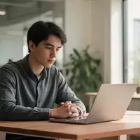Ein junger Berufseinsteiger sitzt nachdenklich an einem Schreibtisch in einem modernen Büro vor einem Laptop. - Foto: über boerse-global.de