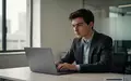 Ein junger Berufseinsteiger sitzt an einem Schreibtisch in einem modernen Büro und arbeitet an einem Laptop. - Foto: über boerse-global.de