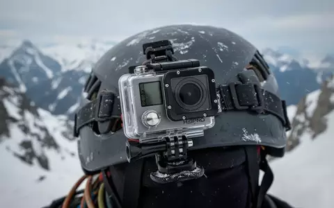 Eine Actionkamera montiert auf einem Kletterhelm vor einer verschneiten Bergkulisse. - Foto: über boerse-global.de