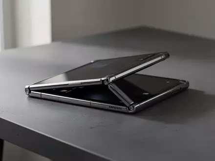 Ein hochwertiges faltbares Smartphone liegt halb geöffnet auf einem dunklen, minimalistischen Schreibtisch. - Foto: über boerse-global.de
