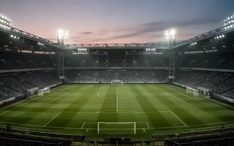 Ein leeres Fußballstadion bei Dämmerung mit Flutlichtbeleuchtung auf dem grünen Rasen. - Foto: über boerse-global.de