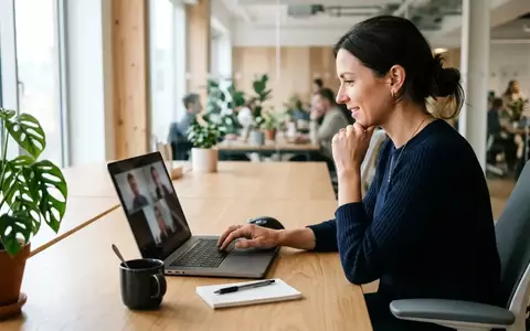 Eine Person arbeitet an einem modernen Laptop in einem hellen Büro während einer Videokonferenz. - Foto: über boerse-global.de