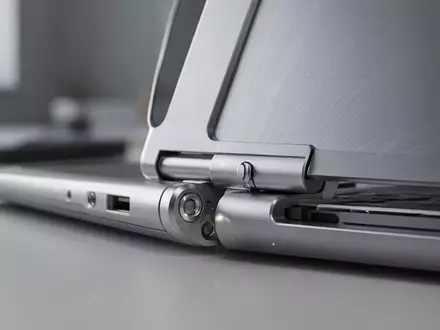 Nahaufnahme eines präzise gefertigten Laptop-Scharniers aus gebürstetem Aluminium in einer professionellen Arbeitsumgebung. - Foto: über boerse-global.de